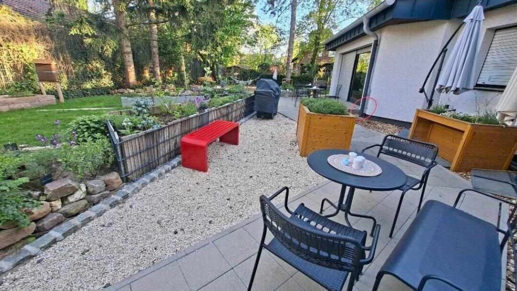 Der Garten der Thomas Begegnungsstätte mit Hochbeeten, Sitzmöglichkeiten, Bäumen und einer Rasenfläche